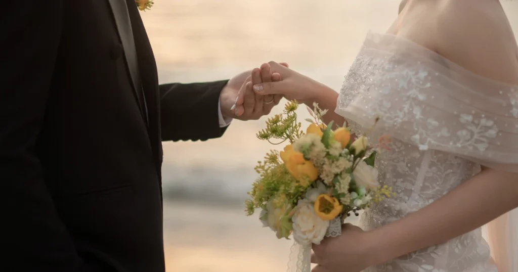 Pengantin berjalan bersama sambil bergandengan tangan, dengan buket bunga dan dekorasi pernikahan di sekitarnya.