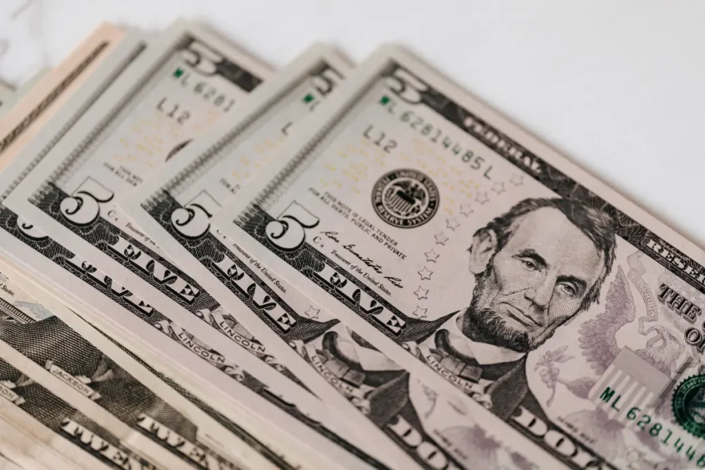 Beberapa lembar uang dolar Amerika tersusun di atas meja, menggambarkan anggaran biaya untuk pernikahan di Bali.