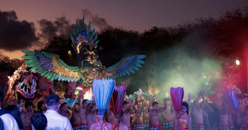 Sejumlah penari dan peserta mengikuti pertunjukan budaya Bali dengan kostum tradisional, patung Garuda bersayap, dan efek asap berwarna.
