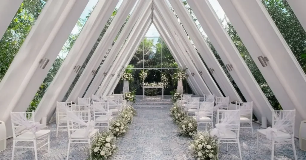Venue pernikahan berbentuk segitiga dengan kursi putih dan rangkaian bunga untuk upacara pernikahan di Bali.