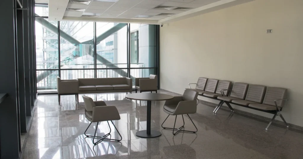 Ruang pre-function area dengan sofa, kursi, dan meja yang digunakan sebagai tempat tunggu sebelum acara ballroom.