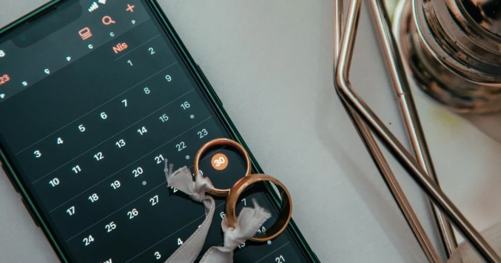 Cincin pernikahan diletakkan di atas kalender digital, menggambarkan pemilihan tanggal pernikahan yang tepat pada 2027.
