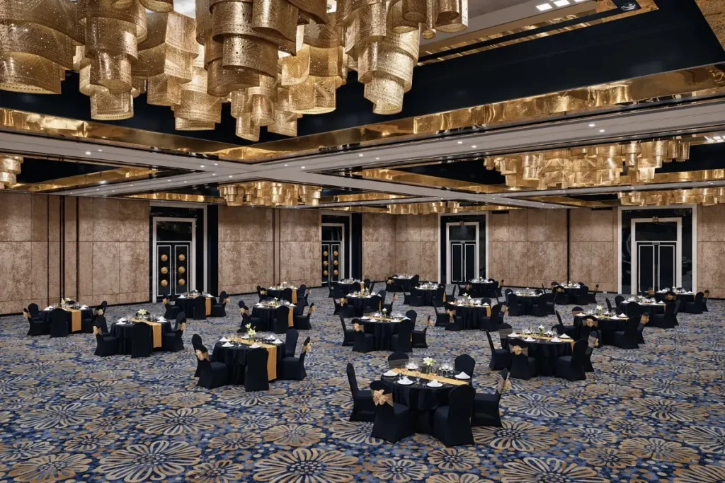 Ballroom luas dengan meja bundar dan kursi tertata, cocok untuk acara keluarga yang dihadiri anak-anak dan orang dewasa.